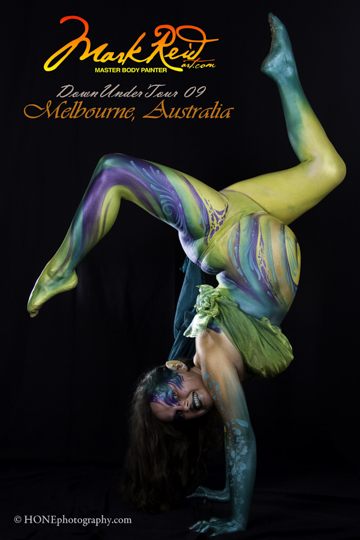 pregnant woman in green and white body paint doing a hand stand